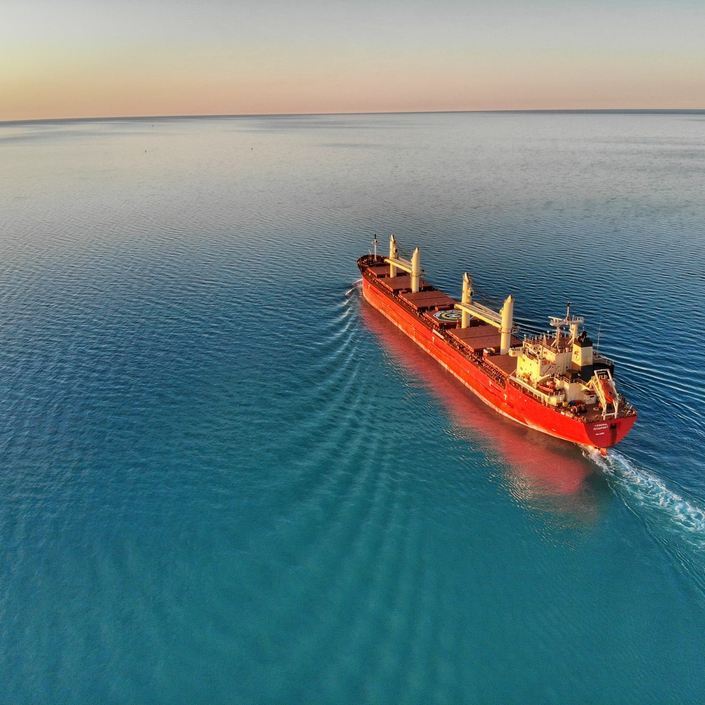 red and white cargo ship at middle of ocean